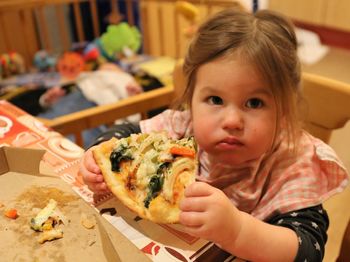 Portrait of cute girl eating pizza at home