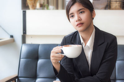 Confident businesswoman sitting with coffee mug at cafe