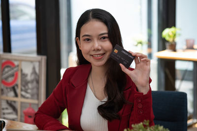 Portrait of smiling young woman using phone on table