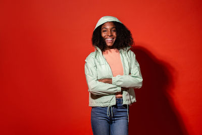 Portrait of smiling woman standing against red wall