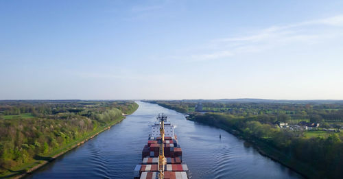 Container ship on river against sky