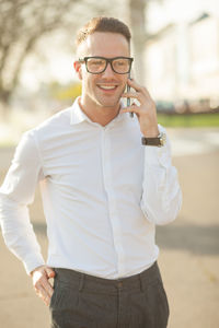 Portrait of man wearing sunglasses while standing on smart phone