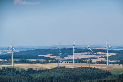 Windmills on field against sky