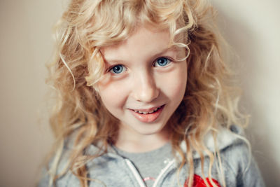 Closeup portrait of beautiful smiling caucasian blonde girl with long hair on light background. 