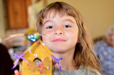 Close-up portrait of cute smiling girl holding toy home