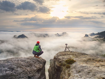 People on rock against sky during sunset