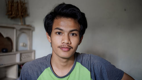 Portrait of young man against wall at home