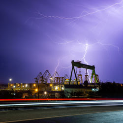 Lightning over illuminated city against sky at night