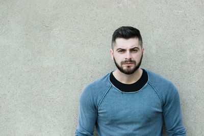 Portrait of young man standing against wall