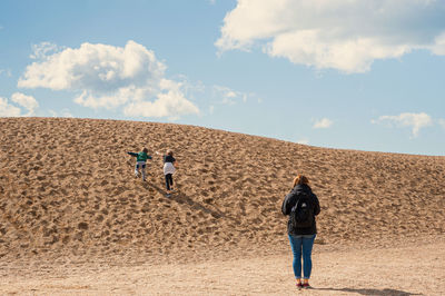 Rear view of people walking on sand dune in desert