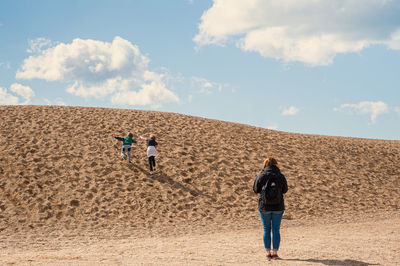 Rear view of people walking on desert