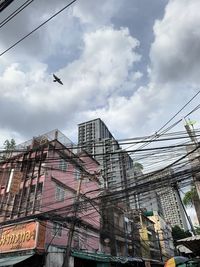 Low angle view of birds flying over buildings in city