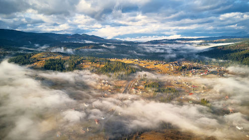 Colorful autumn morning, fog mountain valley. village covered clouds. fall rural misty cold  morning