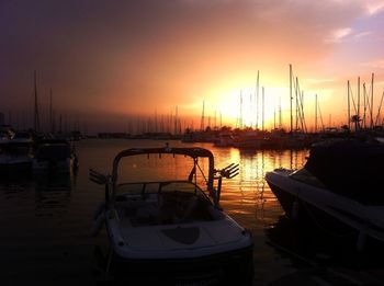 Sailboats moored at harbor during sunset