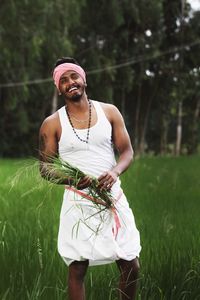 Young man holding unwanted grass removed then smiling on field