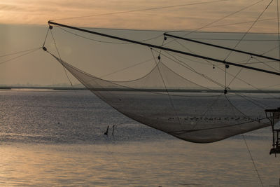 Sailboats moored on sea against sky during sunset