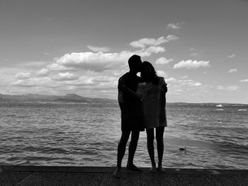 Couple hugging in front of the coastline of garda lake in italy