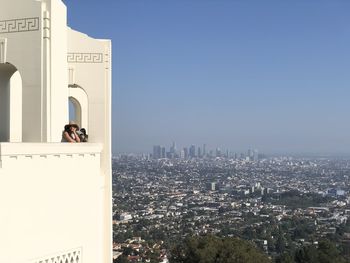 Woman photographing city buildings against clear sky