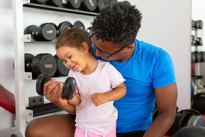 Father teaching daughter to lift dumbbell