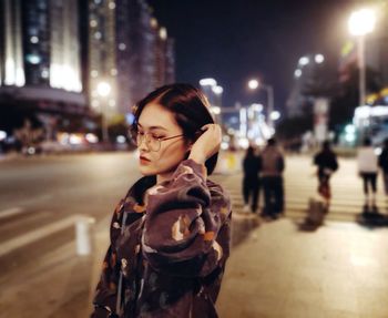 Portrait of man standing on city street at night