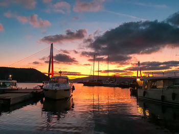 Sailboats moored on sea against sky during sunset