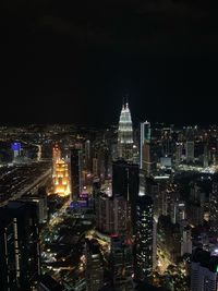 Illuminated buildings in city against clear sky at night