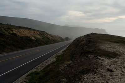 Road leading towards mountain against sky