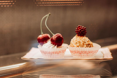 Sweet tiny cakes with fluffy cream and red cherries