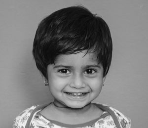 Close-up portrait of smiling innocent girl against wall