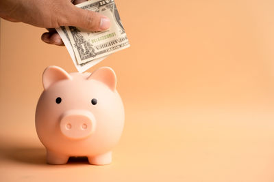 Close-up of hand holding candle against colored background