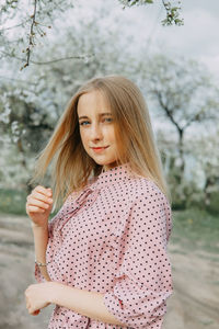 Blonde girl on a spring walk in the garden with cherry blossoms. female portrait, close-up. 