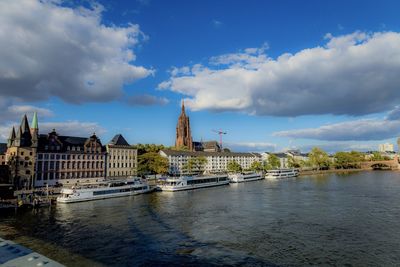 Buildings by river against sky