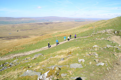 People on field by mountain against sky