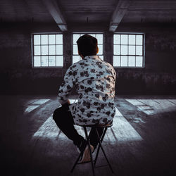 Rear view of man sitting on table at home