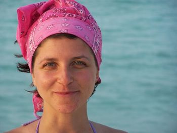 Close-up portrait of smiling mature woman wearing bandana against sea