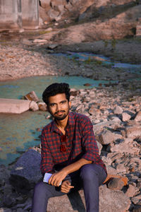 Portrait of young man sitting on rock