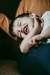 Boy laughing while lying on bed