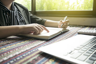 Businesswoman reading book while working at desk in office