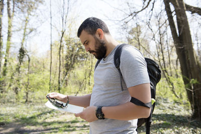 Hiker holding map while standing in forest