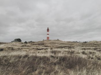 Lighthouse on grassy field against sky