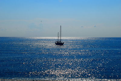 Sailboat sailing in sea against blue sky