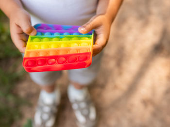 Little boy plays square rubber fidget toy pop it. rainbow-colored anti stress and tactile toy.