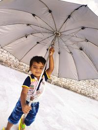 Portrait of happy girl standing on umbrella