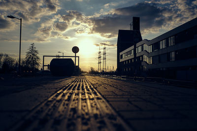 Surface level of railroad tracks against sky during sunset