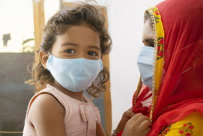 Portrait of cute girl wearing flu mask against white background