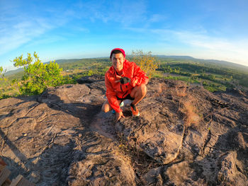 Full length of young man on rock against sky