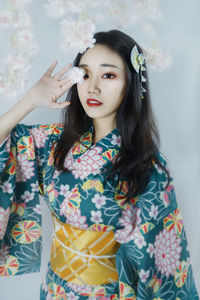 Portrait of young woman standing against wall