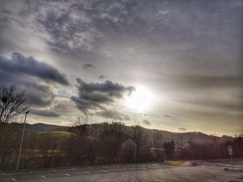 Road amidst trees on field against sky during sunset