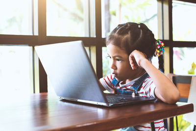 Portrait of girl sitting on table at home