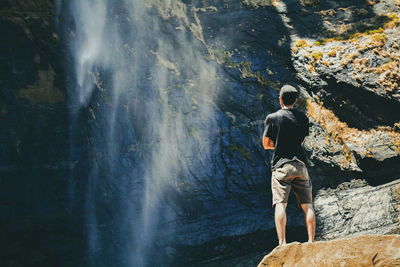 Rear view of man standing against waterfall